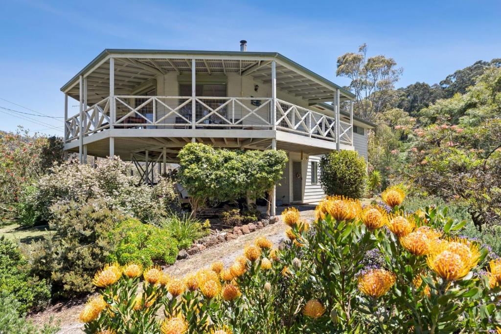 a house on a hill with flowers in front of it at Tumbaramba in Wye River