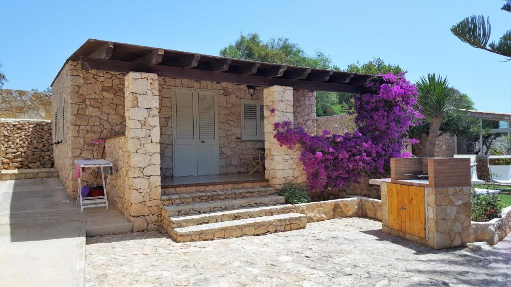 a small house with purple flowers on it at Pretty Damuso Style Villa in Lampedusa