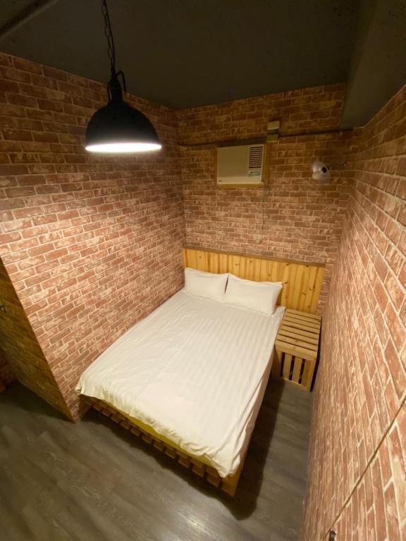 a bedroom with a bed in a brick wall at Hive Bed and Backpacker蜂巢膠囊旅店 in Hualien City