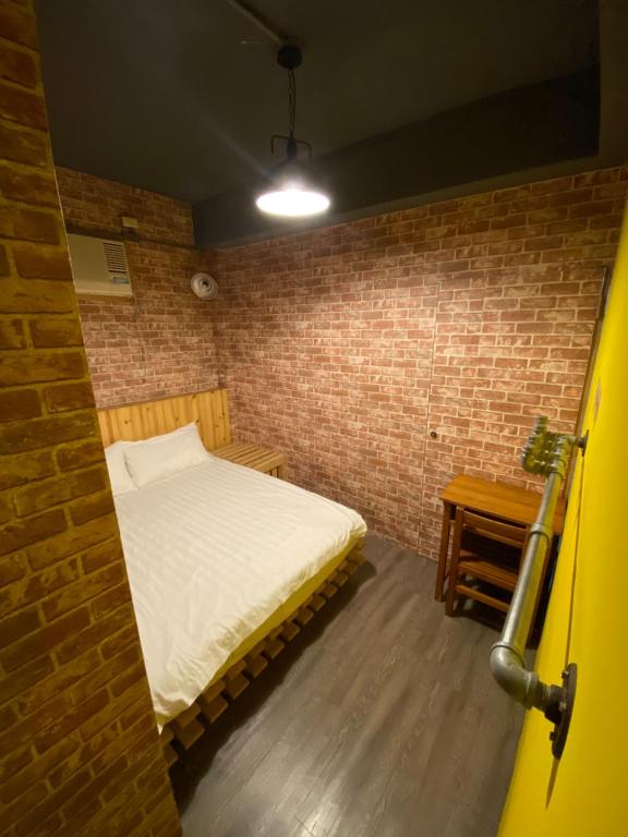 a small room with a bed in a brick wall at Hive Bed and Backpacker蜂巢膠囊旅店 in Hualien City