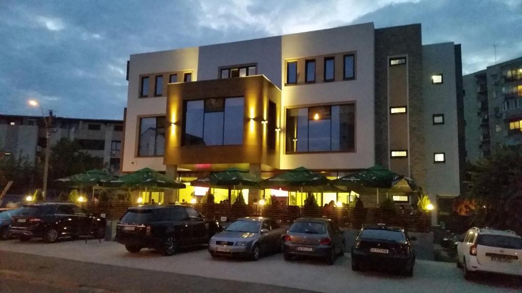 a building with cars parked in a parking lot at Hotel Excellence in Bucharest