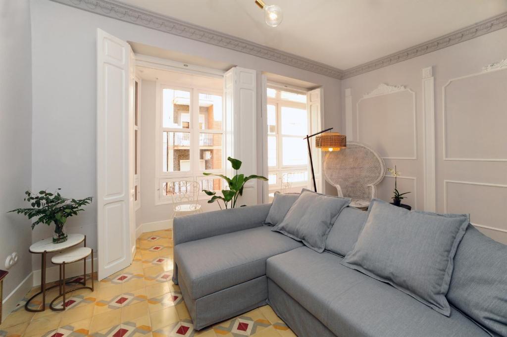uma sala de estar com um sofá cinzento e janelas em La Casa de Santa Florentina-Parking incluido - 100 m2 em Cartagena
