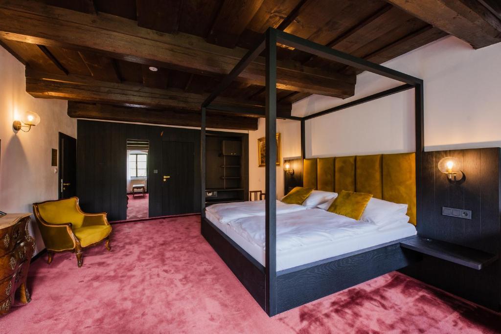 una camera con letto a baldacchino e sedia gialla di Villa Conti a Cesky Krumlov