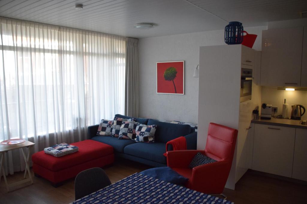 een woonkamer met een blauwe bank en rode stoelen bij Duinstraatje 3 in Zoutelande