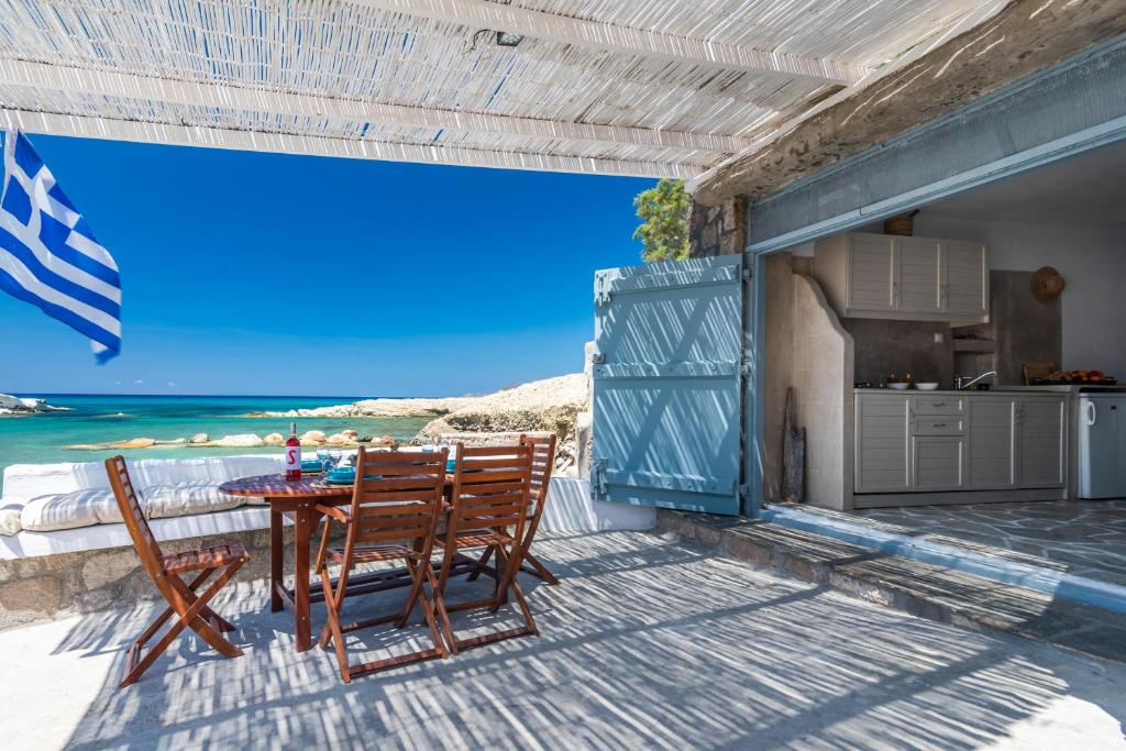 un patio con mesa y sillas en la playa en Sarakiniko Boat House en Mandrakia