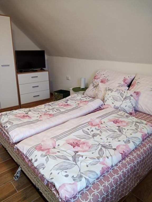 a bed with pink flowers on it in a room at Borostyán Vendégház in Balatonkeresztúr