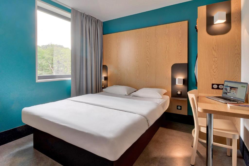 Un dormitorio con una cama y un escritorio con una computadora portátil. en B&amp;B HOTEL Bayonne Tarnos, en Tarnos