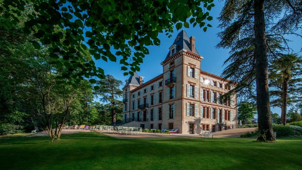 a building with a tower on top of a grass field at Château de Fiac - Luxurious Hôtel & Spa in Fiac