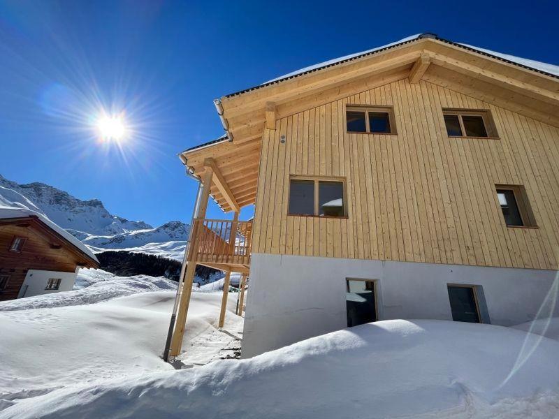 a building in the snow with the sun behind it at Chalet Sternenhimmel in Arosa