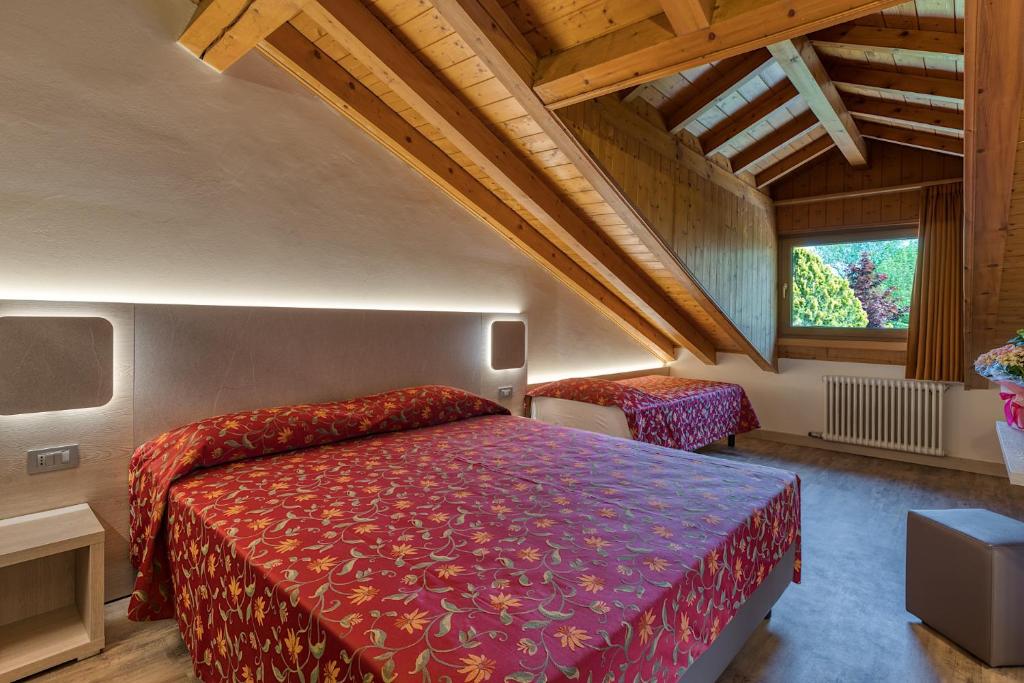 1 dormitorio con 1 cama con colcha roja en Hotel Aurora, en Cimego