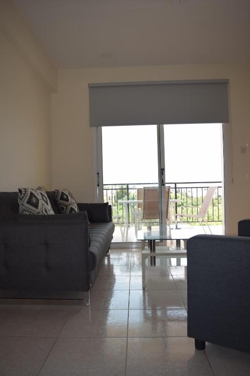 a living room with black couches and a large window at Eden Heights Sea View Apartment 203 - By IMH Travel & Tours in Paphos