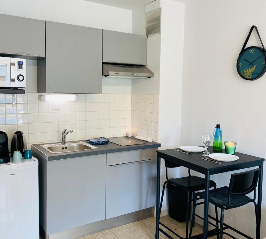 a small kitchen with a table and a sink at KASA VOYTIER Parking privé & Wifi - Balcon & Ascenseur in Saint Etienne