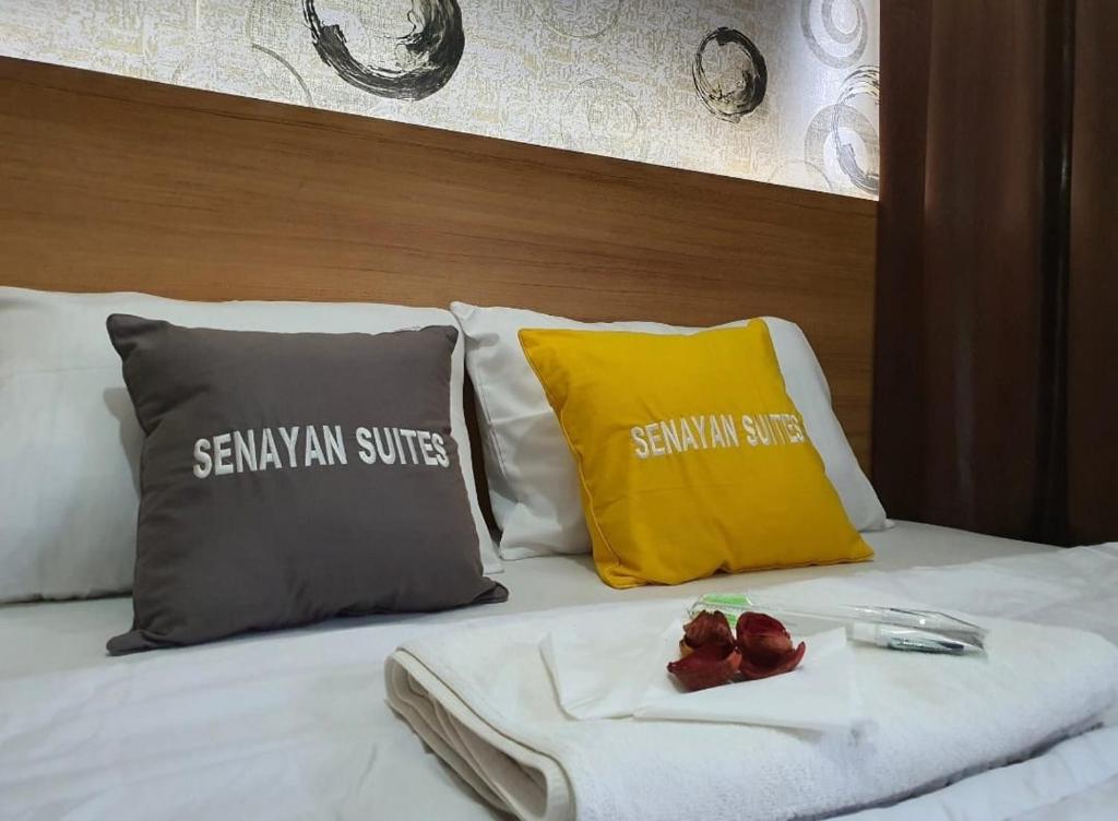 a bed with two pillows and a tray of food on it at SENAYAN SUITES in Jakarta