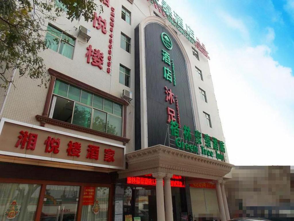 un bâtiment avec des panneaux de néon sur son côté dans l'établissement GreenTree Inn Guangzhou Panyu Chimelong Paradise Business Hotel, à Canton