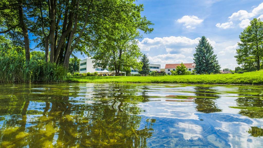 ein Wasserkörper mit Bäumen und Gebäuden im Hintergrund in der Unterkunft Seepark Hotel am Wandlitzsee in Wandlitz