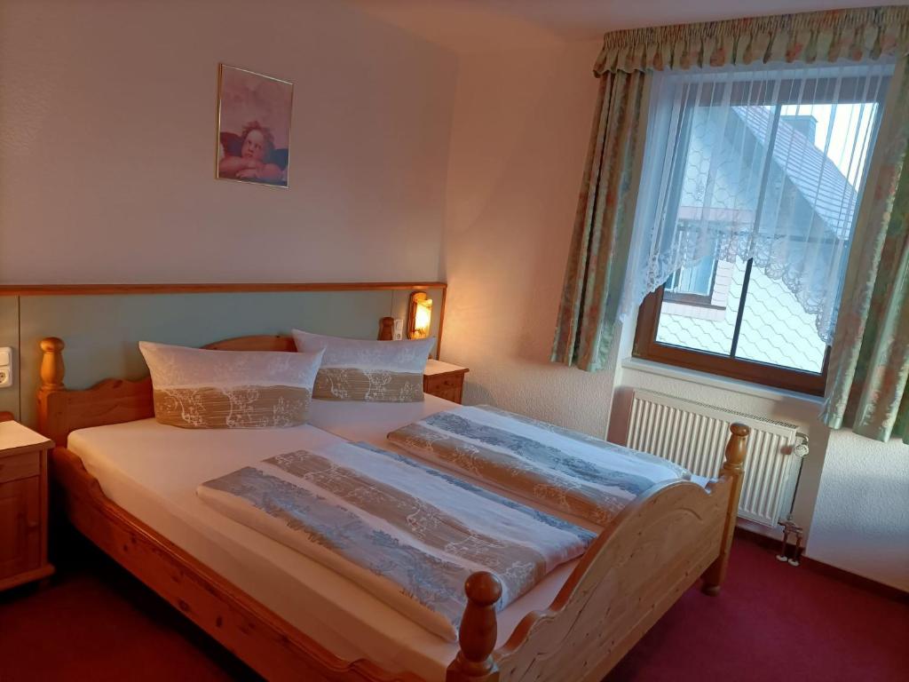 Schlafzimmer mit einem großen Bett und einem Fenster in der Unterkunft Pension Drei Elstern in Schierke