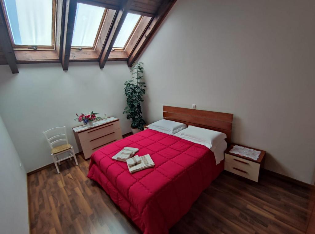 1 dormitorio con 1 cama roja y 2 toallas en Apartments Vila Bovec, en Bovec