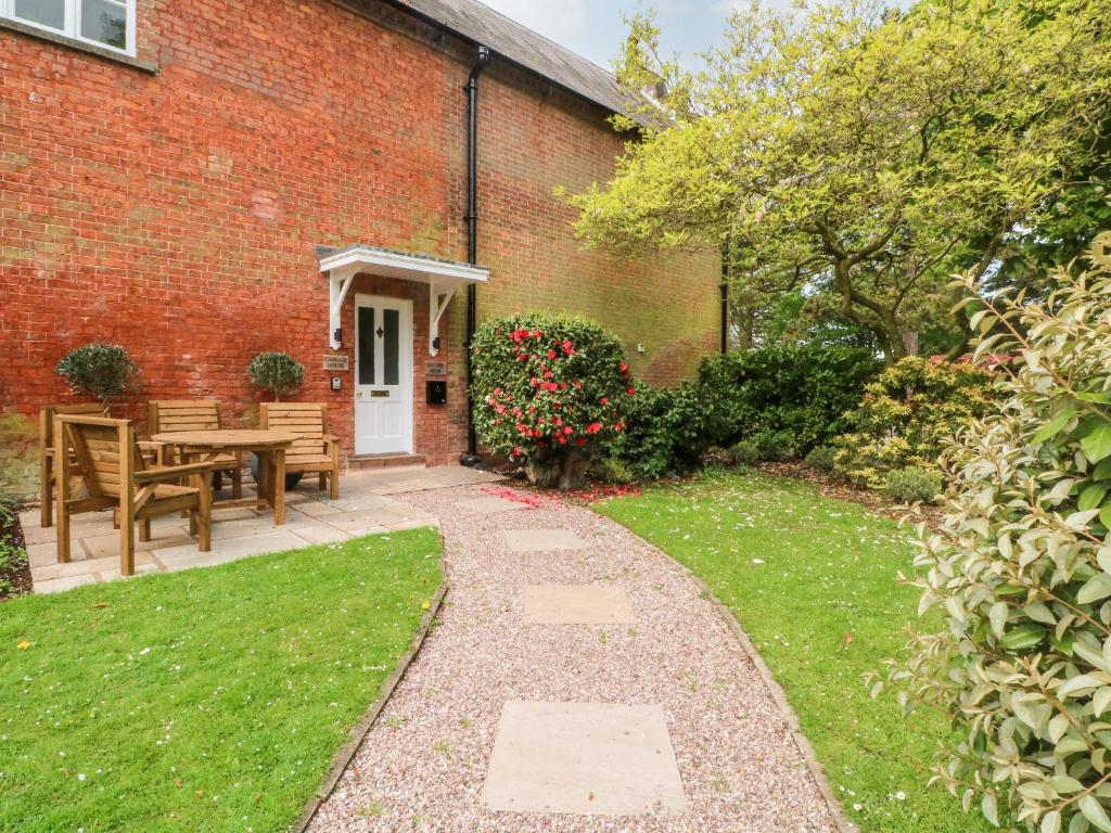 a brick house with a pathway leading to a patio at Carriage House in Macclesfield