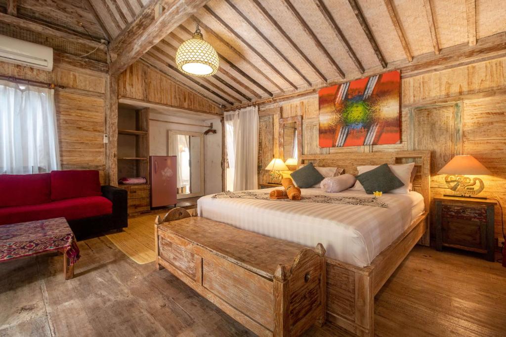 een slaapkamer met een groot bed en een rode bank bij Secret Wooden Cabins in Jimbaran