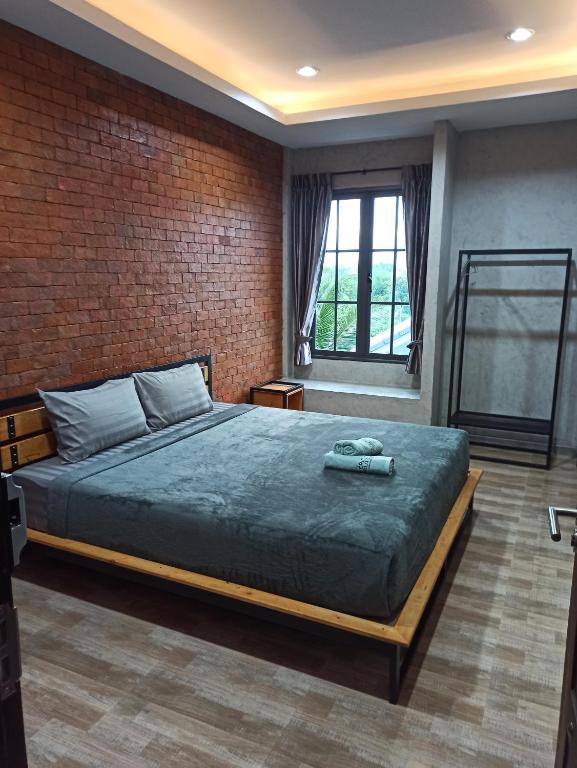 a bedroom with a bed and a brick wall at Bearry Loft in Nakhon Ratchasima