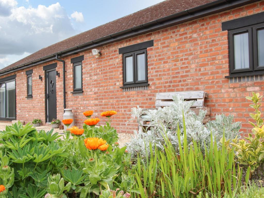 una casa in mattoni con giardino di fronte di Lindens Barn a Shrewsbury
