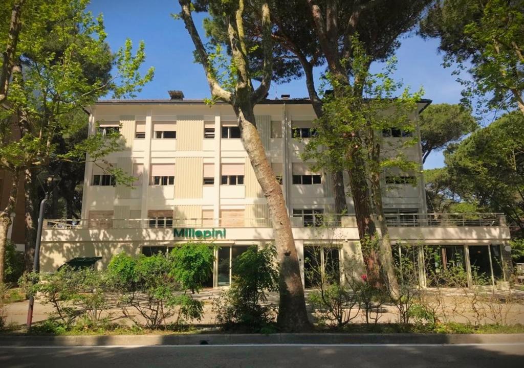 a white building with trees in front of it at Hotel Millepini in Marina Romea