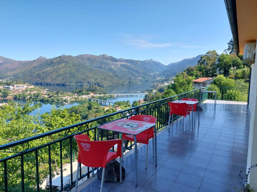 a balcony with red tables and chairs overlooking a river at Alojamento Local Lindo Verde in Vieira do Minho