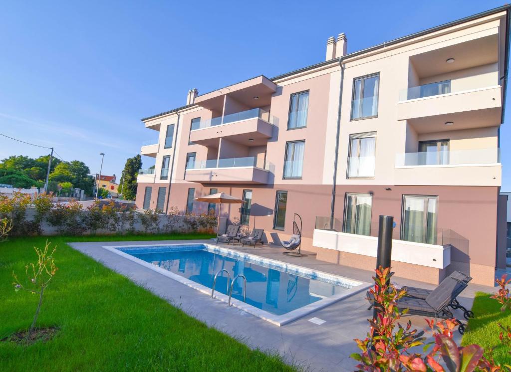 a building with a swimming pool in front of a yard at Luxury apartment Faro with sea view and swimming pool in Premantura