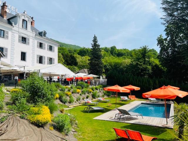 a resort with a pool and chairs and umbrellas at Hôtel Restaurant Le Repère in Vizille
