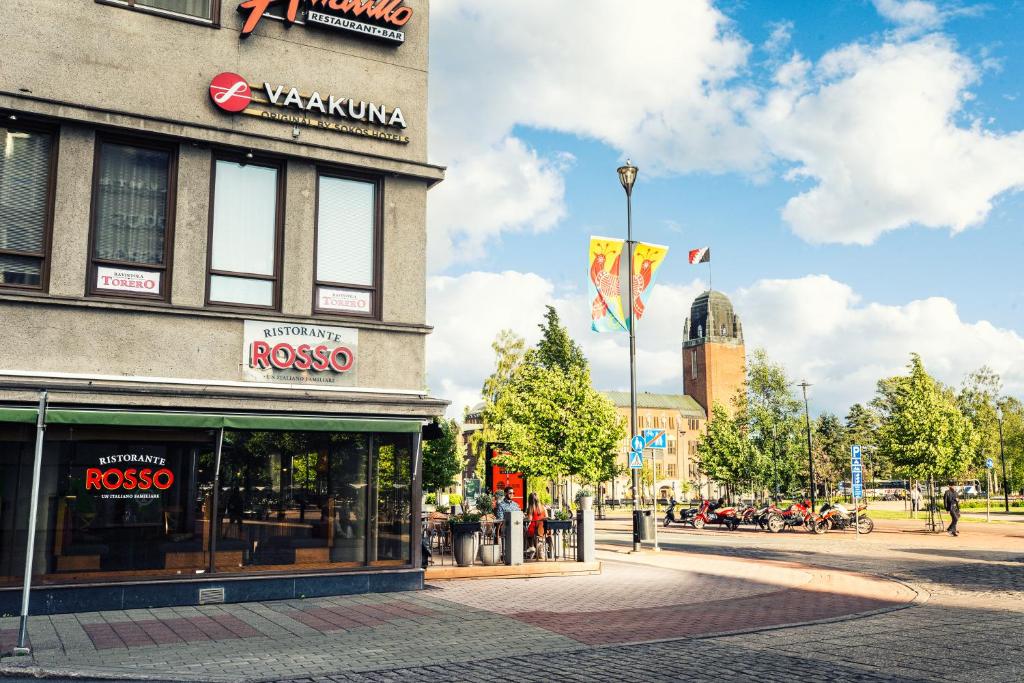 een gebouw in een stadsstraat met vlaggen ervoor bij Original Sokos Hotel Vaakuna Joensuu in Joensuu