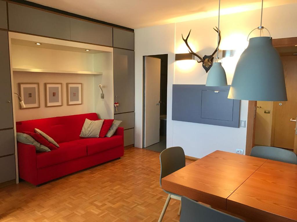 a living room with a red couch and a table at Appartamento con vista sull'Alpe di Siusi in Bulla