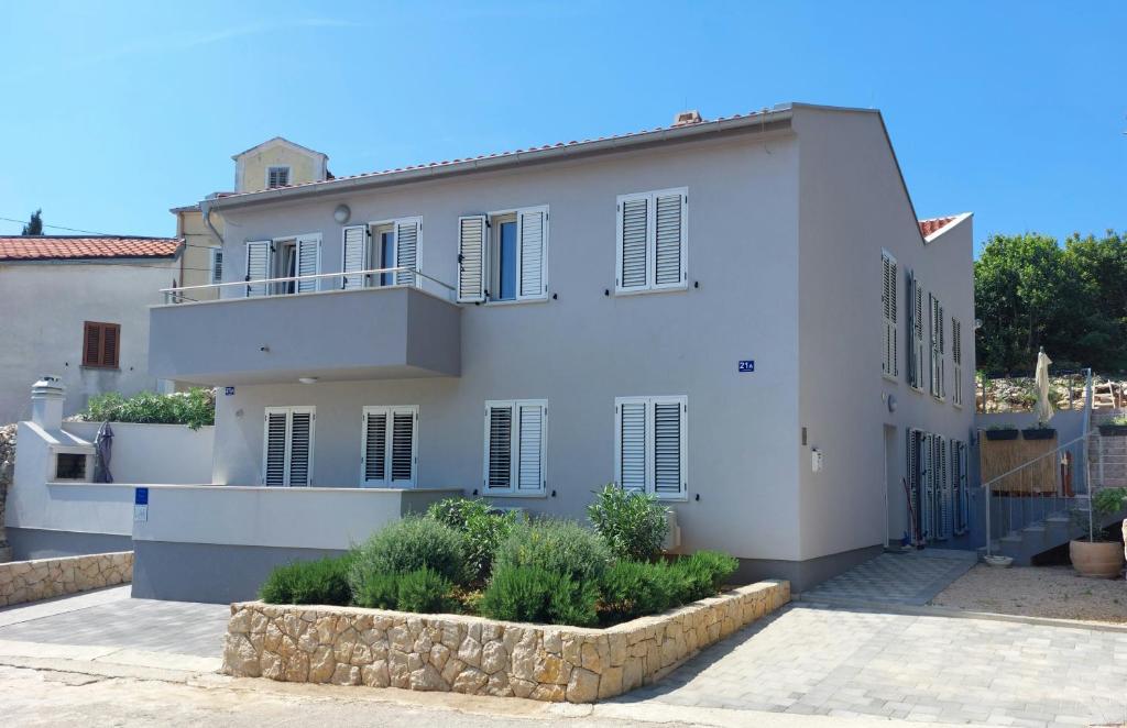 a white house with a balcony on top of it at Apartmani Beatrice in Mali Lošinj