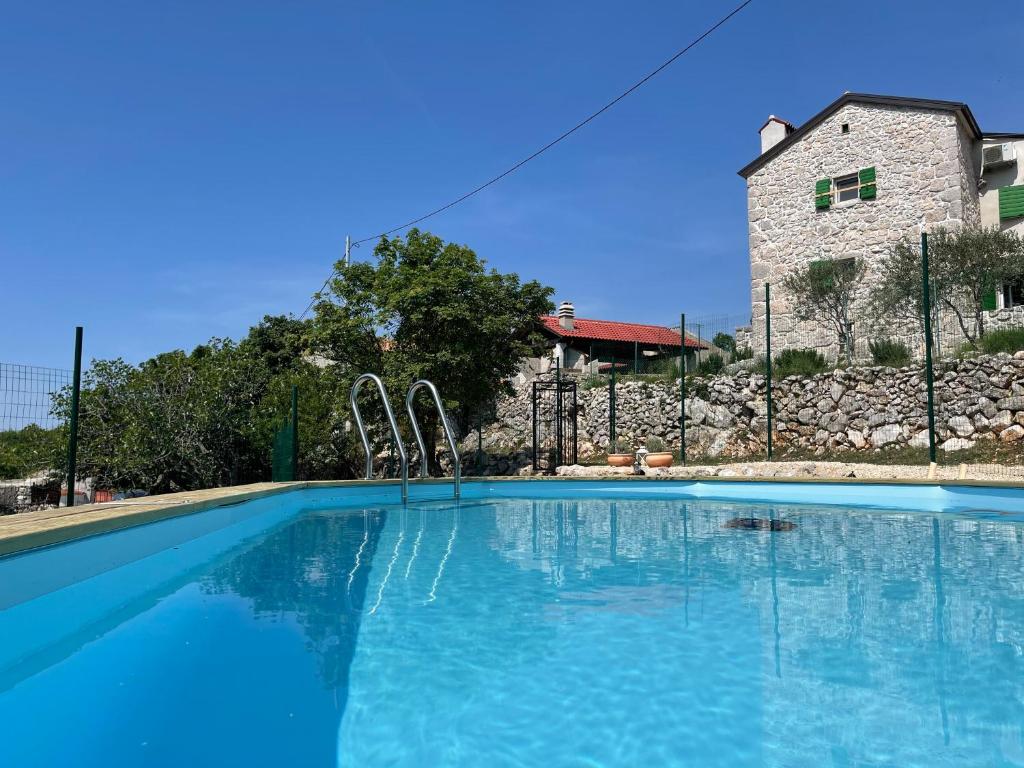 einem großen Pool vor einem Steingebäude in der Unterkunft Villa Ana with jacuzzi & swimming pool in Cres