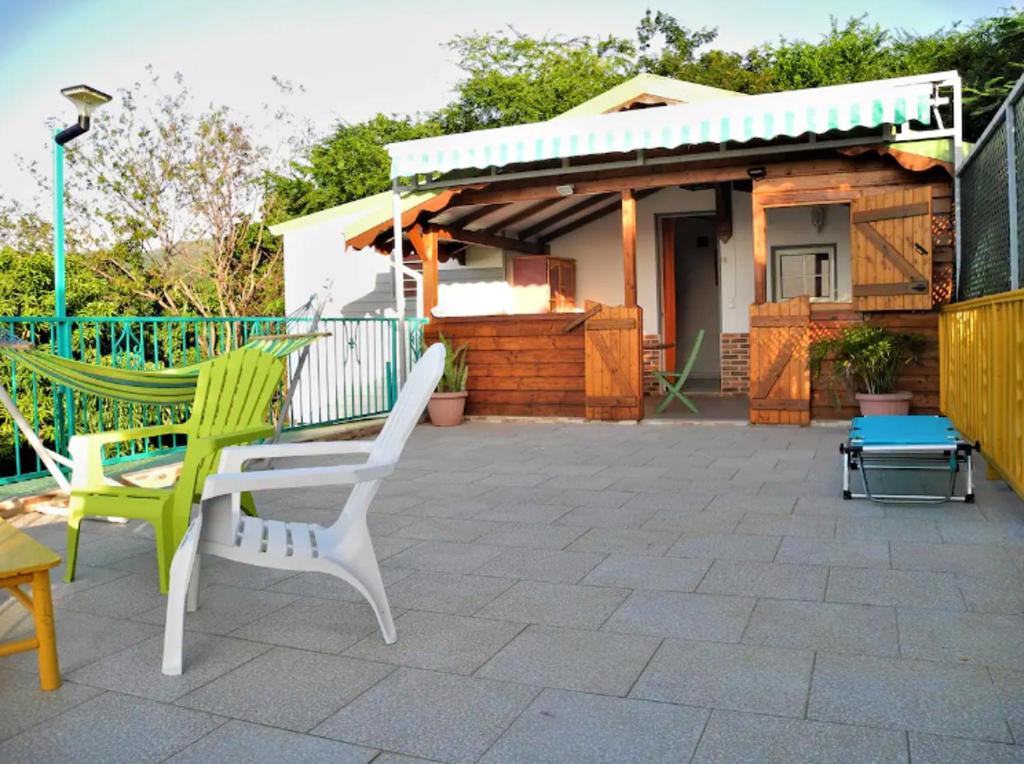 un patio con 2 sillas y una casa en Bungalow d'une chambre avec vue sur la mer jardin clos et wifi a Deshaies, en Deshaies
