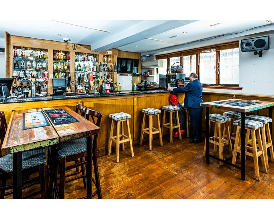 a man standing at a bar in a restaurant at Crown Hotel in Callander