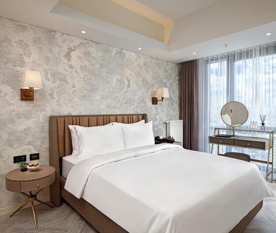 een slaapkamer met een groot wit bed en een bureau bij Wanda Vista Residence in Istanbul