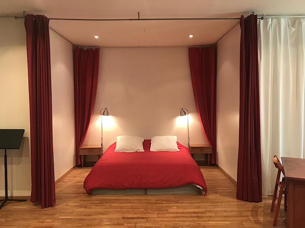 a bedroom with a red bed with two pillows at Gîte Le Salon de Musique in Tourny