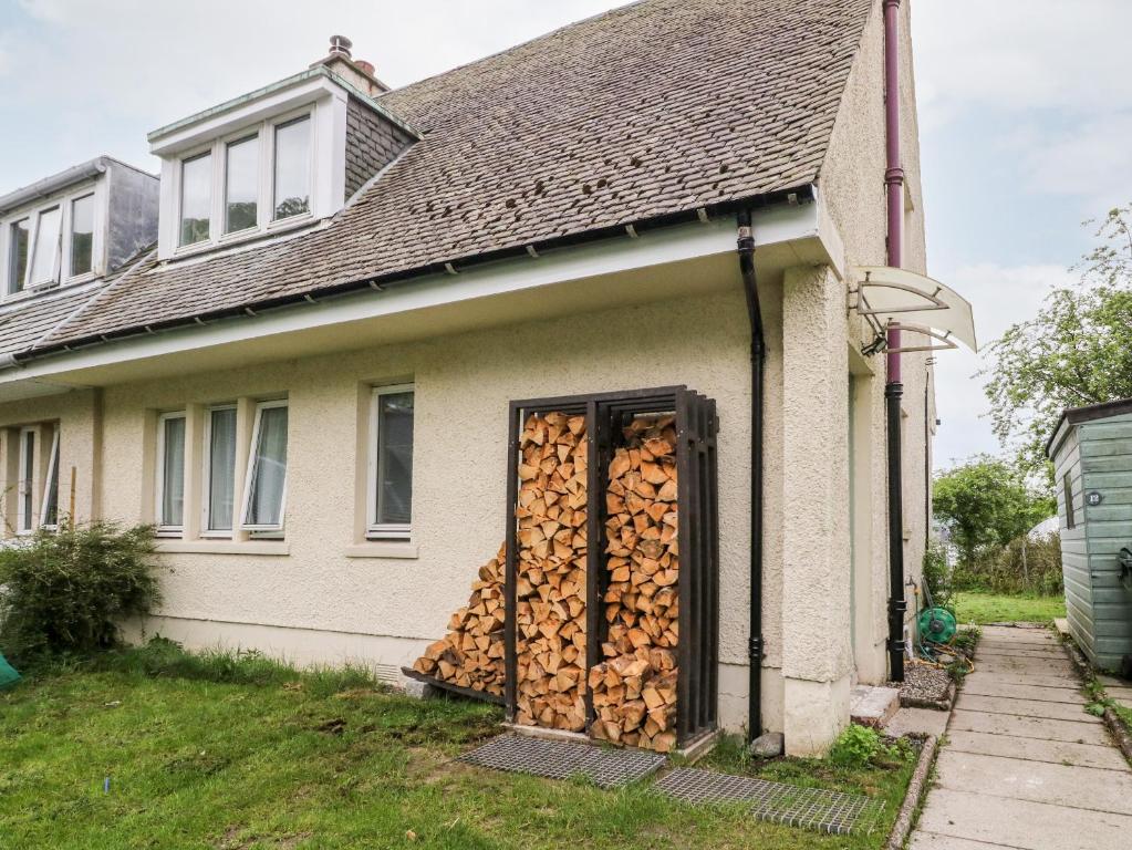 a pile of fire wood on the side of a house at 12 Kenmore Cottages in Oban