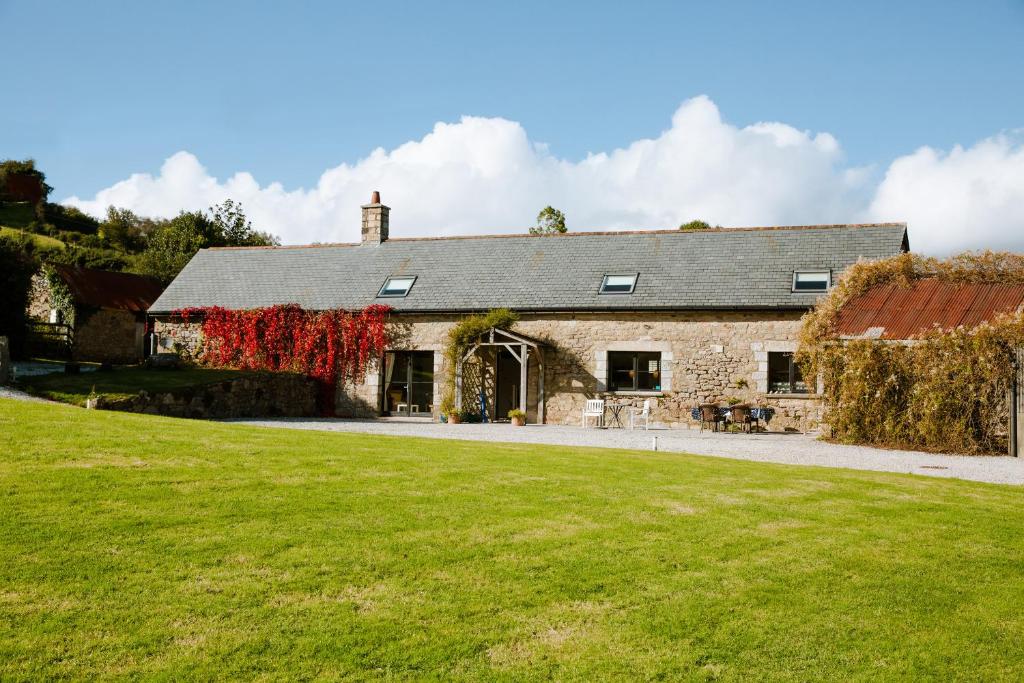 an old stone house with a green lawn in front of it at Higher Weddicott Barn in Newton Abbot