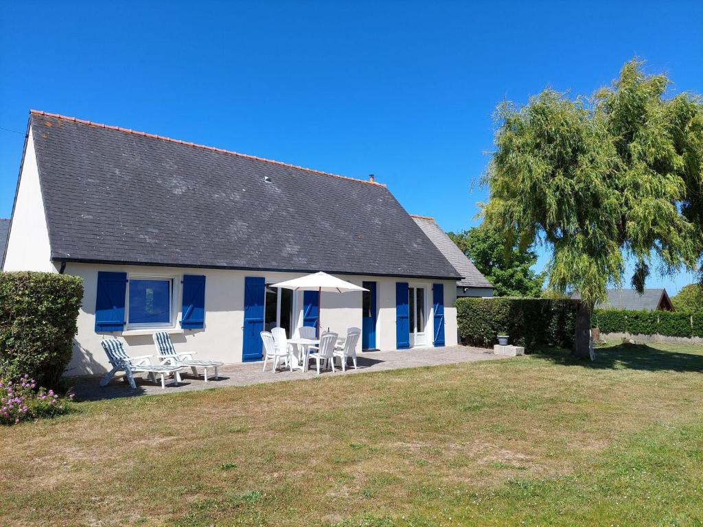 une maison bleue et blanche avec des chaises et une table dans l&#39;établissement Single storey holiday home near the beach, Santec, à Santec