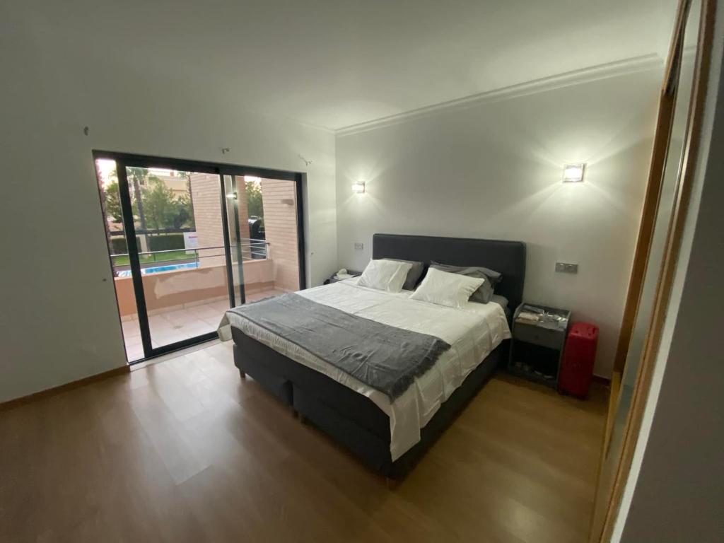 um quarto com uma cama e uma porta de vidro deslizante em Janelas do Oceano - Casa de Ferias T3 Vilamoura em Vilamoura