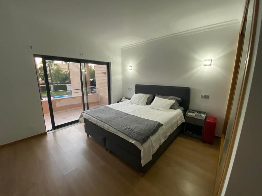 a bedroom with a bed and a sliding glass door at Janelas do Oceano - Casa de Ferias T3 Vilamoura in Vilamoura