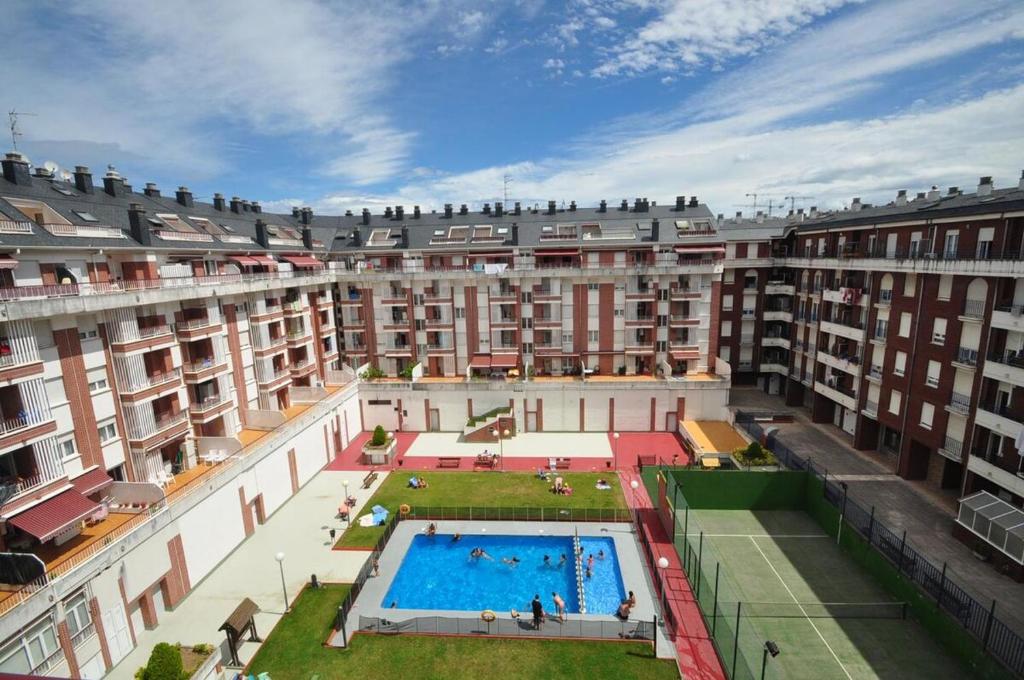 a large building with a swimming pool in front of it at Apt Las Olas Cotolino con parking a 2' de la playa in Castro-Urdiales