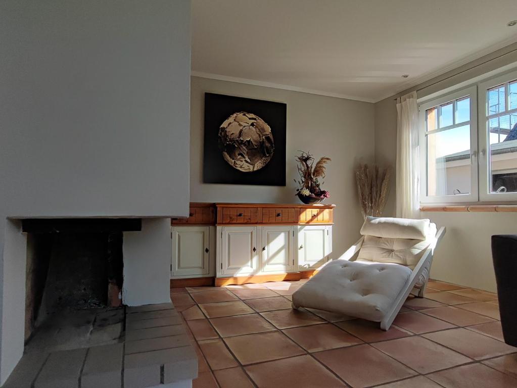 a living room with a white chair and a fireplace at BooHouse in Zingst