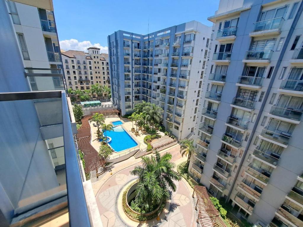 an apartment balcony with a swimming pool and buildings at Palm Tree Villas by Ann in Manila