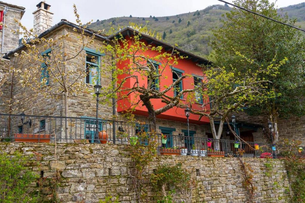 une maison rouge avec un mur en pierre dans l'établissement Shamrock Elati Retreats, à Elati