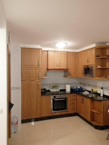 a kitchen with wooden cabinets and a stove top oven at Piso en Raxó in Raxó