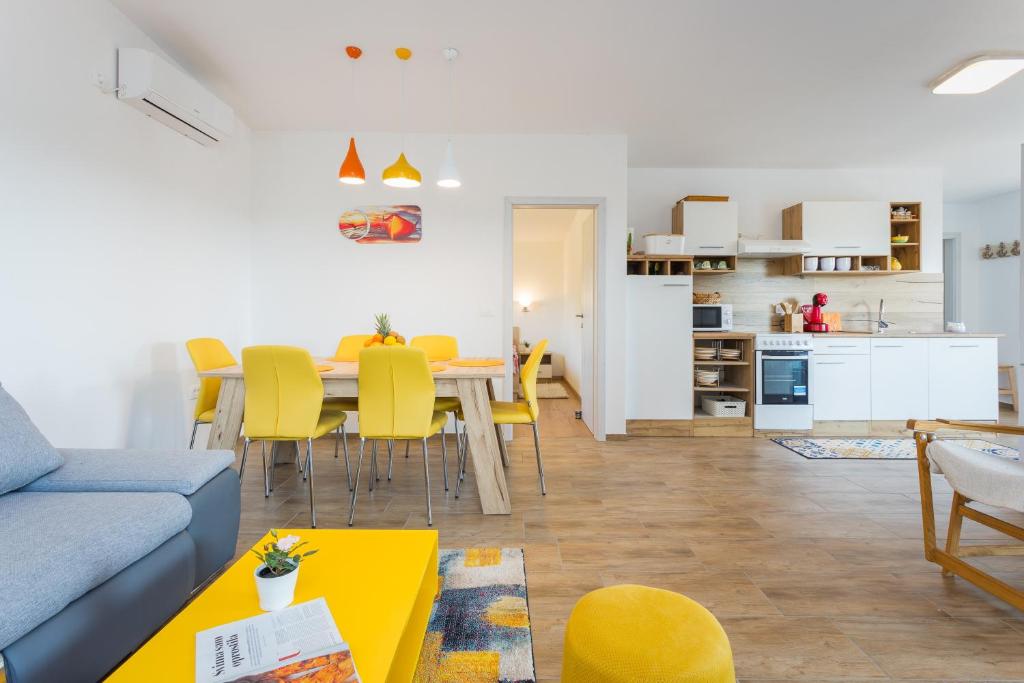 salon i kuchnia ze stołem i żółtymi krzesłami w obiekcie Sunny Sunny Peroj w mieście Vodnjan