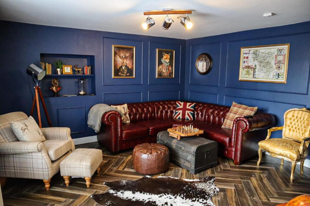 a living room with a leather couch and chairs at The Old Butchers Cottage in Matlock