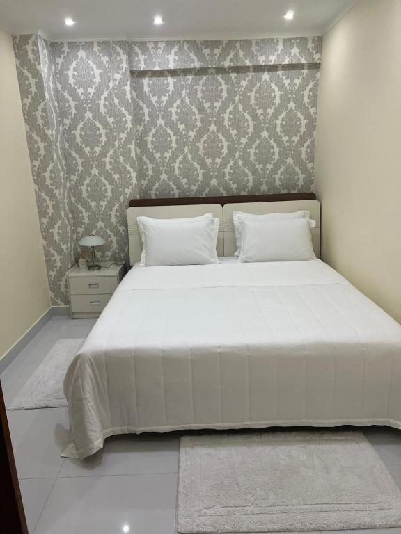 a bedroom with a large white bed with a wall at Wonderful 1 bedroom apartment in Luanda in Luanda